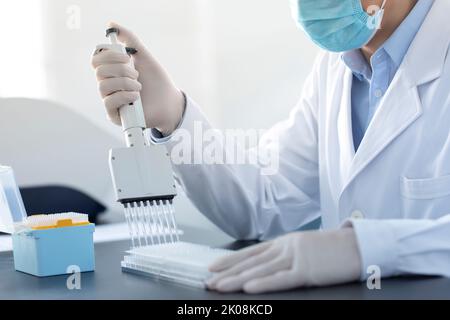 Un scientifique chinois pipetteur des échantillons en laboratoire Banque D'Images