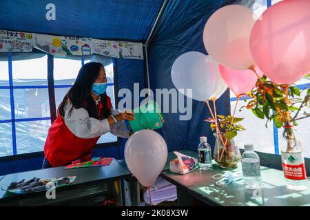 (220910) -- LUDING, le 10 septembre 2022 (Xinhua) -- Luo Lian organise des livres dans une salle de classe sous tente au refuge de secours en cake de l'école secondaire Luding no 2 dans le comté de Luding, dans la province du Sichuan, dans le sud-ouest de la Chine, le 10 septembre 2022. Luo Lian, 32 ans, est professeur de maternelle dans la ville de Lengqi, dans le comté de Luding. Après un séisme de magnitude 6,8 qui a secoué le comté de Luding, elle s'est portée volontaire pour travailler au refuge de secours aux cake de l'école secondaire de Luding no 2, où plus de 800 villageois, dont environ 50 enfants de la ville de Detuo, l'une des régions les plus touchées, ont été temporairement relocalisés. Avec d'autres volontaires, Luo Banque D'Images