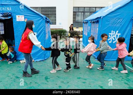 (220910) -- LUDING, le 10 septembre 2022 (Xinhua) -- Luo Lian conduit les enfants à une salle de classe sous tente au refuge de secours en cake de l'école secondaire Luding no 2 dans le comté de Luding, dans le sud-ouest de la province du Sichuan en Chine, le 10 septembre 2022. Luo Lian, 32 ans, est professeur de maternelle dans la ville de Lengqi, dans le comté de Luding. Après un séisme de magnitude 6,8 qui a secoué le comté de Luding, elle s'est portée volontaire pour travailler au refuge de secours aux cake de l'école secondaire de Luding no 2, où plus de 800 villageois, dont environ 50 enfants de la ville de Detuo, l'une des régions les plus touchées, ont été temporairement relocalisés. Avec d'autres volontaires, Luo Banque D'Images