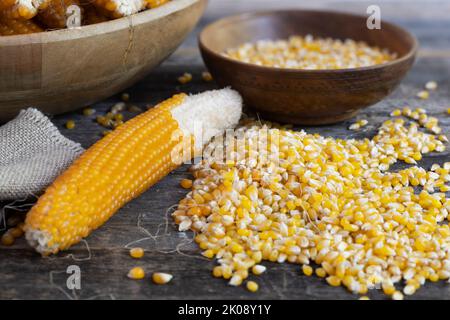 Récolte du maïs soufflé de l'épi avec des grains et des épis dans des bols en bois et sur la table. Banque D'Images