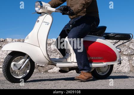 Lambretta TV classique scooter italien en rouge et blanc bicolore, homme dans des vêtements décontractés à cheval sur une journée ensoleillée. Ballintoy, Royaume-Uni - 10 septembre 2022. Banque D'Images