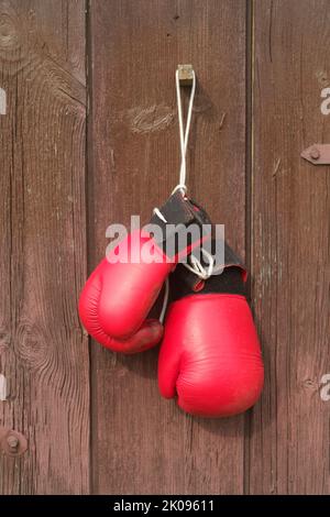Vieux gants de boxe rouge en cuir pendent sur le fond du bois en marron Banque D'Images