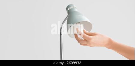 Femme en ampoule lampe sur fond gris Banque D'Images