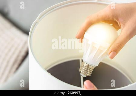 Femme changeant d'ampoule dans la lampe à la maison, gros plan Banque D'Images