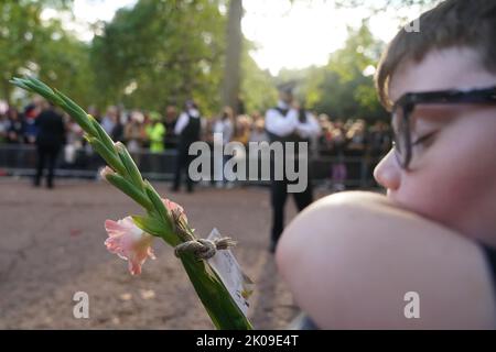 Un jeune garçon semble s'endormir alors qu'il attend le roi Charles II et la reine pour retourner à Clarence House, Londres, de Buckingham Palace, après le décès de la reine Elizabeth II jeudi. Date de la photo: Samedi 10 septembre 2022. Banque D'Images