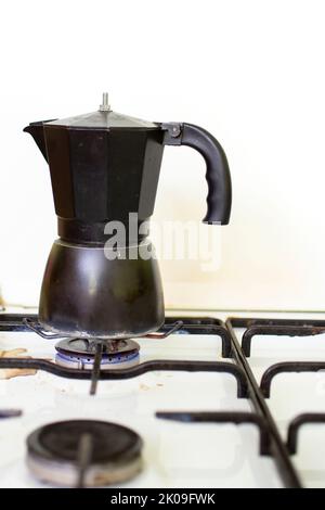 cafetière italienne noire sur une cuisinière à brûleur blanc. Banque D'Images