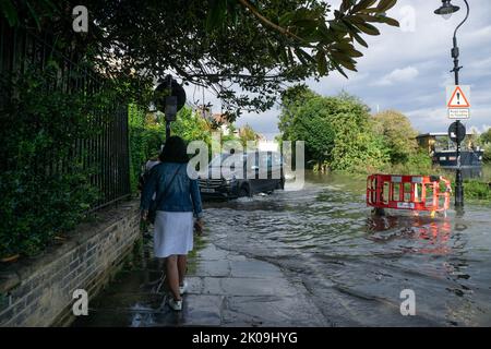 Londres, Angleterre, Royaume-Uni. 10th septembre 2022. Après les orages, un piéton observe la conduite d'un taxi noir sur la rive inondée de la Tamise, près de Chiswick, dans l'ouest de Londres. Cristina Massei/Alamy Live News Banque D'Images