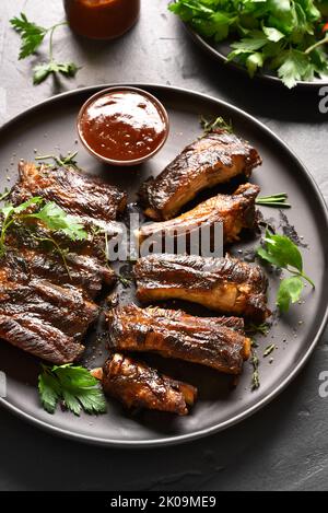 Côtes de porc grillées sur plaque sur fond de pierre noire. Vue rapprochée Banque D'Images
