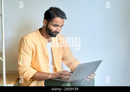 Utilisateur indien assis à la maison tapant sur l'ordinateur portable à l'aide d'un ordinateur. Banque D'Images