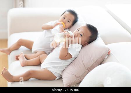 Les petits bébés chinois boivent du lait dans des biberons Banque D'Images