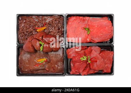 Vue de dessus de steaks de bœuf cru assortis, foie et cuisses dans des plateaux isolés sur fond blanc Banque D'Images