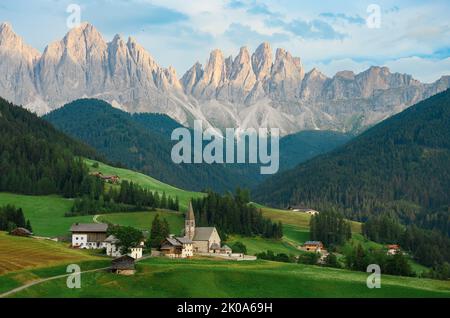 Vue imprenable sur la vallée de Funes (Val di Funes) avec l'église Santa Maddalena et la chaîne de montagnes du parc naturel de Puez Odle au loin. Banque D'Images