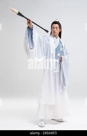 Jeune homme chinois en costume antique écrivant la calligraphie Banque D'Images