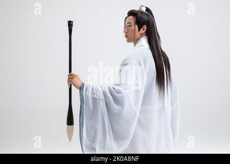 Jeune Chinois en costume ancien tenant une brosse à encre Banque D'Images