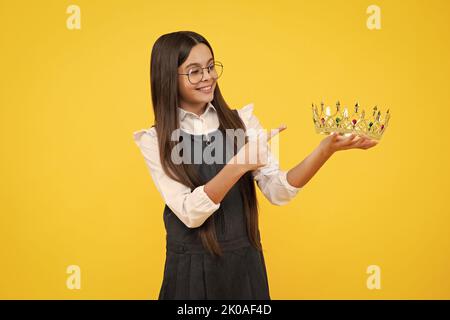 Portrait d'une jeune fille ambitieuse avec couronne, sensation de princesse, confiance. Couronne princesse enfant sur fond de studio isolé. Bonne fille visage Banque D'Images