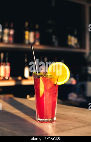 Il sert un cocktail de fruits d'été rouges et violets frais au comptoir du bar par beau temps. Mise au point sélectionnée, faible profondeur de champ. Banque D'Images