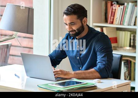 Homme d'affaires indien travaillant à distance sur un ordinateur portable, assis au bureau à domicile. Banque D'Images