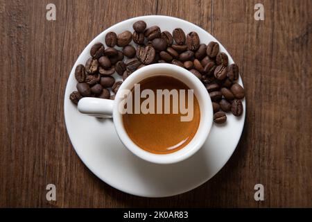 Grains de café avec une tasse d'espresso sur fond de bois Banque D'Images
