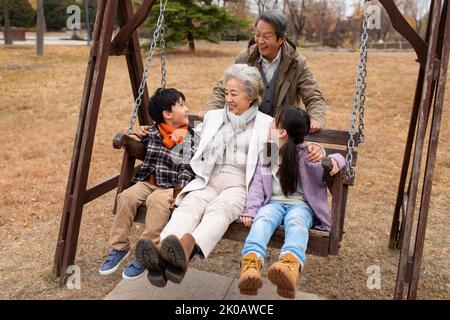 Bonne famille chinoise jouant sur une balançoire Banque D'Images