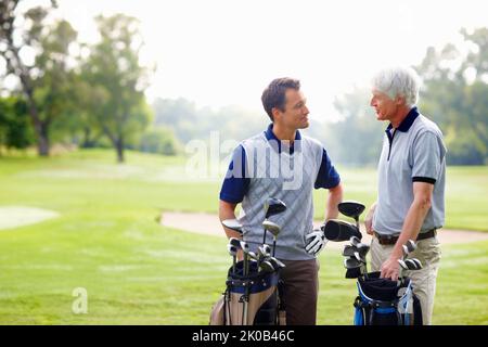 Deux golfeurs en discussion. Père et fils debout sur le terrain de golf et discutant entre eux. Banque D'Images