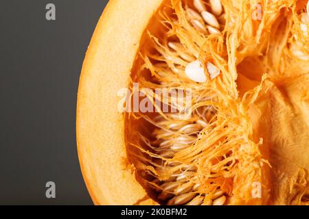 Coupez la moitié de la citrouille d'Halloween avec de la pulpe pleine de graines mûres. Gros plan en studio Banque D'Images