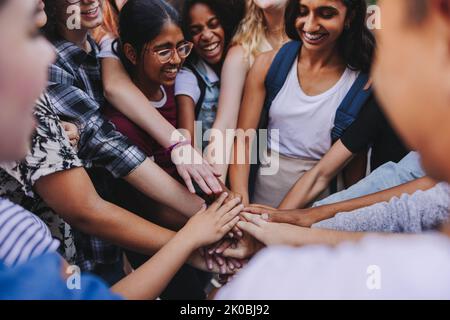 Groupe d'adolescents multiculturels souriant avec joie tout en mettant les mains ensemble dans un caucus. Les jeunes de la génération Z symbolisent la communauté et le thé Banque D'Images