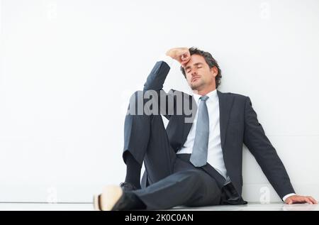 Coup d'œil rapide. Beau homme d'affaires prenant une petite sieste assis contre le mur. Banque D'Images