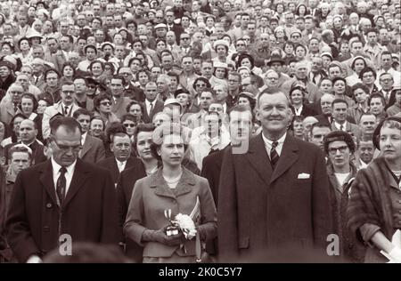 La reine Elizabeth II avec le gouverneur du Maryland Theodore McKeldin (à droite) et le président de l'Université du Maryland Wilson Homer 'Bull' Elkins (à gauche), à un match de football de Maryland Terrapins vs. The North Carolina Tar Heels à College Park, Maryland. (ÉTATS-UNIS) Banque D'Images