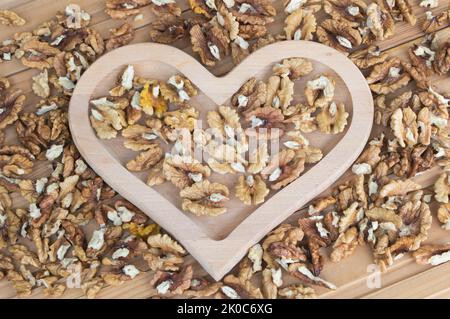 Noyaux de noyer dans une plaque en forme de coeur en bois gros plan - avantages du concept de wanlnuts Banque D'Images