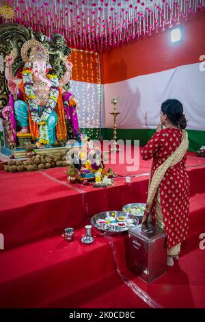Mumbai, Inde, 05 septembre 2022 - Une femme priant devant une belle idole de Lord Ganesha à un mandal à Mumbai pour le festival de Ganesh Chaturthi Banque D'Images