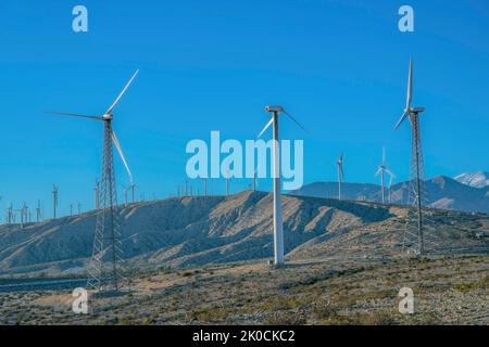 Éoliennes avec tours en treillis et en acier tubulaire au sommet d'une chaîne de montagnes désertiques en Californie. Moulins à vent au sommet d'une montagne désertique contre le Th Banque D'Images