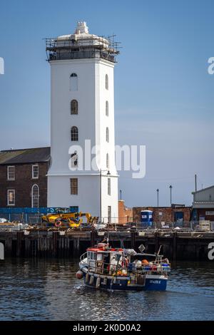 Un bateau de pêche arrive au quai de poissons de North Shields par une journée ensoleillée, avec le Low Light derrière Banque D'Images