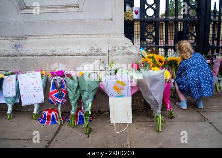 Une jeune fille qui a placé un bouquet de fleurs à côté d'autres hommages floraux devant Buckingham Palace après la mort de la reine Elizabeth II Enfant Banque D'Images