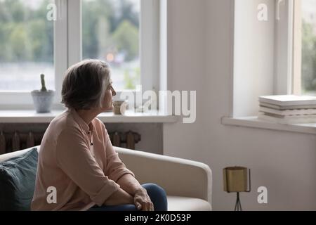 Femme solitaire attentionnés à la retraite assise sur un canapé à la maison Banque D'Images