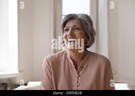 Joyeuse et excitée femme mûre regardant loin, en riant Banque D'Images