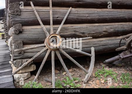 Sous le ciel couvert de Cody, Wyoming se trouve les vestiges d'une vieille ville de l'époque du Far West. Une roue à rayons repose sur le côté d'une cabine en rondins Banque D'Images