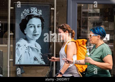 Wimbledon, Londres, Royaume-Uni. 11 septembre 2022. Les piétons marchent devant un portrait de la reine Elizabeth II affiché sur la fenêtre du coiffeur à Wimbledon qui est mort à l'âge de 96 ans comme le plus long monarque servant au château de Balmoral en Écosse le mercredi 8 septembre. Credit: amer ghazzal / Alamy Live News Banque D'Images