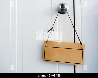 Cadre vide avec espace vide pour le texte sur panneau en bois vintage avec corde accrochée à l'ancien bouton de porte sur fond de porte en bois blanc avec espace de copie, cl Banque D'Images