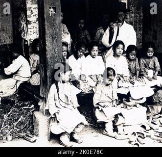 Joseon Era, Corée, 1890-1900. Scène de rue montrant une école publique avec des enfants pauvres et leur enseignant. Banque D'Images