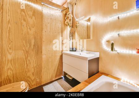 Toilettes et cabine de douche à chasse d'eau avec cloison en verre et rideau situés près de l'évier et de la tablette avec des produits cosmétiques dans les toilettes à la maison Banque D'Images