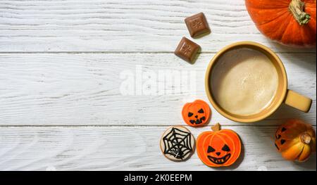 Thème Halloween et café, citrouille d'orange, bonbons et tasse sur table blanche, vue du dessus. Nourriture de vacances sur fond de planches de bois avec espace, plat. Pièce Banque D'Images