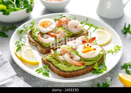 Toast aux crevettes, guacomole d'avocat, arugula et œuf dur Banque D'Images