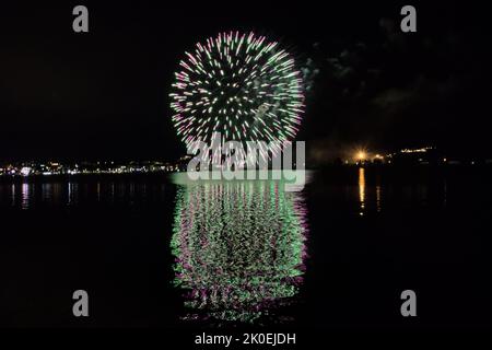 Les feux d'artifice peignent le ciel dans différentes couleurs et sont reflétés dans le lac Miseno, créant une vue à couper le souffle. Banque D'Images