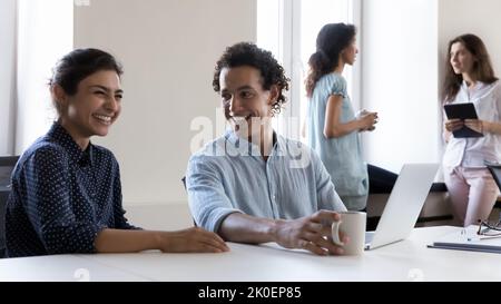 Heureux joyeux joyeux collègues divers bavardant sur le lieu de travail, riant Banque D'Images