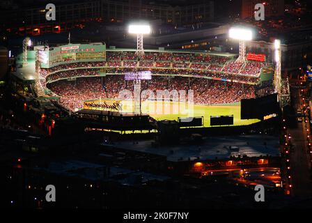 Fenway Park est illuminé la nuit, tandis qu'une grande foule applaudit l'équipe de baseball des Boston Red Sox Banque D'Images