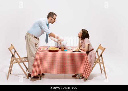 Portrait d'un couple aimant assis à la table, ayant le petit déjeuner isolé sur fond blanc. L'amour Banque D'Images