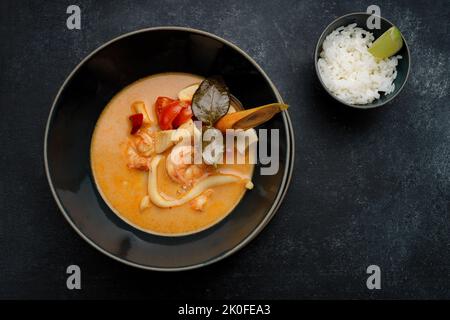 Soupe thaïlandaise aux fruits de mer, sur béton foncé Banque D'Images