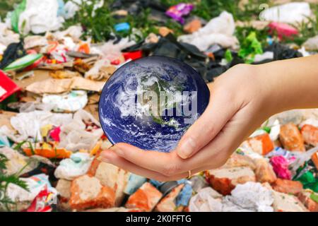 Recentrer la main féminine tenant le globe terrestre sur un arrière-plan poubelle. Concept de protection de l'environnement. La terre entre les mains. À l'exception de la Terre. Éléments de cet imag Banque D'Images