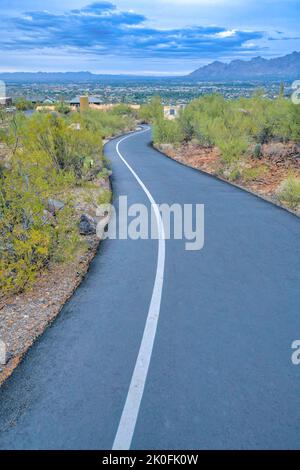 Piste cyclable de descente en asphalte et sentier de randonnée menant aux résidences de Tucson, Arizona. Allée avec voie blanche et vue sur les bâtiments depuis le dessus d'un Banque D'Images