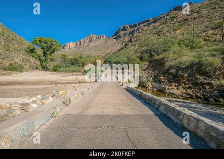 Pont en béton au-dessus de la crique au parc national de Sabino Canyon - Tucson, Arizona. Pont en direction des montagnes du désert avec des cactus saguaro contre le ciel bleu. Banque D'Images